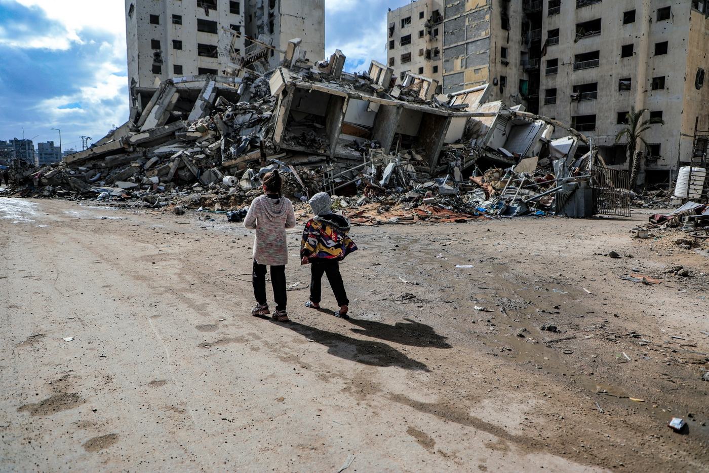 Deux enfants regardent des bâtiments détruits à Gaza.