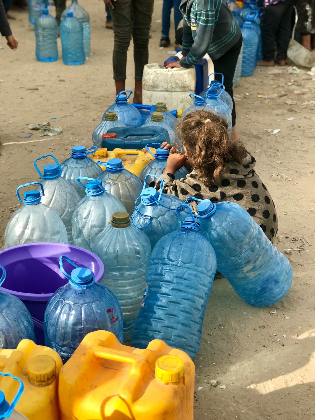 Des personnes rassemblées autour de bouteilles d’eau à Gaza.